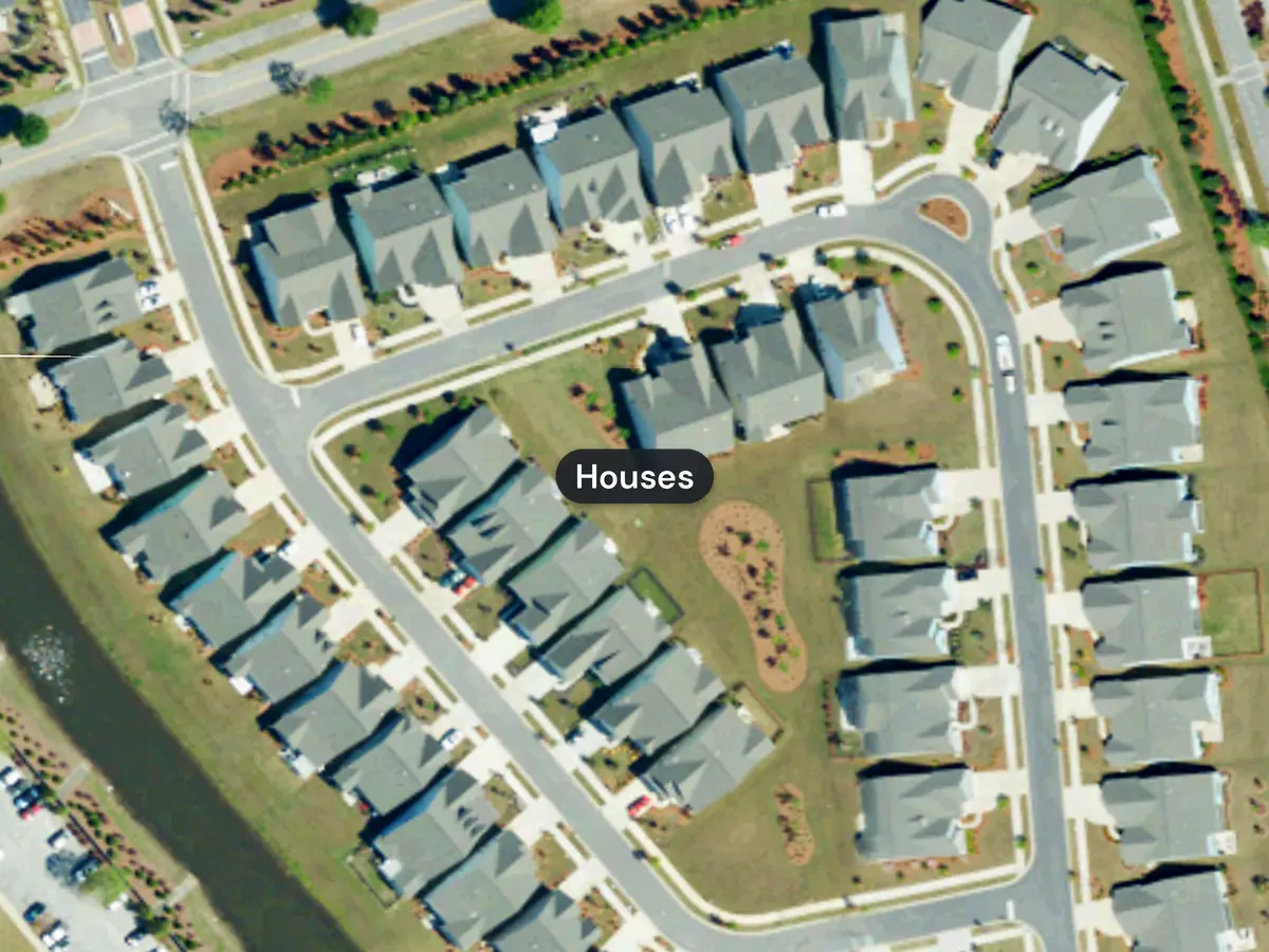 Curving streets lined with single-family houses with gray roofs, small yards and driveways in Del Webb at Grande Dunes, seen from above, with the label Houses