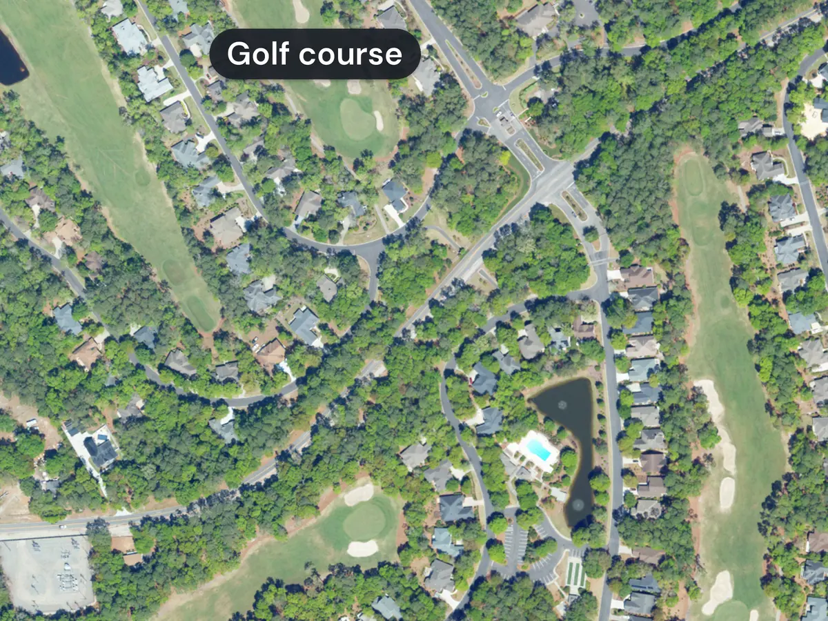 Tidewater Plantation from above: houses under tall trees along curving streets, with green golf fairways and greens on both sides, one labelled Golf course