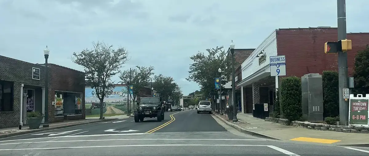 Main Street in downtown Loris, South Carolina, with low brick shop buildings, trees and traffic lights
